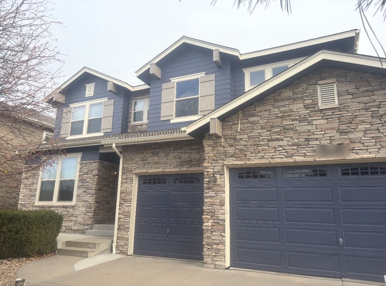 Two-story home repainted in navy siding with cream trim and navy garage doors